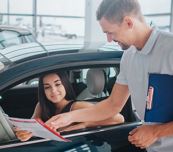 Salesman showing woman car pricing while she sits in the car